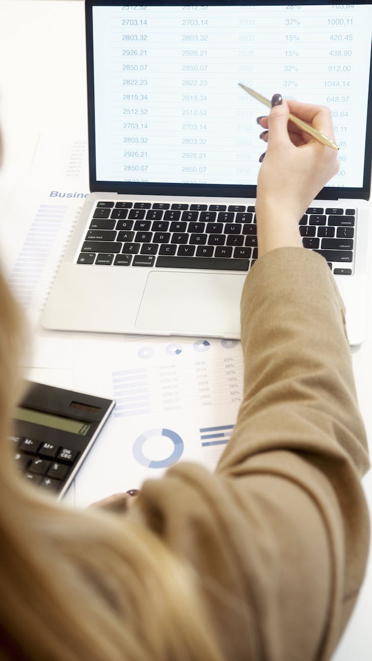 Staff accountant reviewing financial reports with calculator and laptop